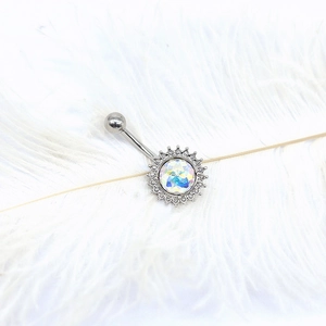 Macro shot of silver sunburst navel ring with iridescent stone and white feather background