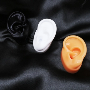 Tre modelli di orecchie in silicone in nero, bianco e pelle per l'esposizione di gioielli