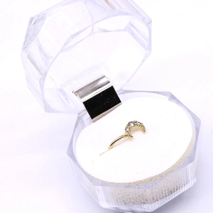 Golden moon-shaped nose ring with five small clear zircon stones on white foam background