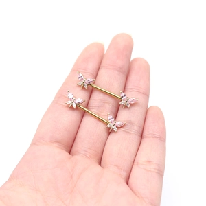 Golden butterfly nipple rings with pink and white zircon stones shown on hand
