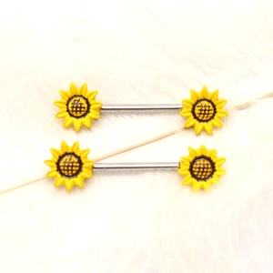 Detail shot of sunflower nipple barbells with yellow petals on a soft white background