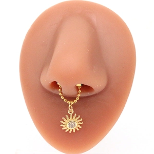 Detailed view of a golden septum ring with sun pendant on a realistic silicone nose model