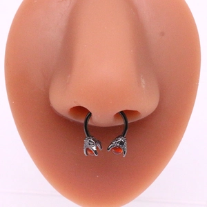 Dettaglio macro del piercing setto con artigli di drago e perle di opale rosso su modello
