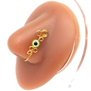 Detailed view of handmade golden wire nose cuff with green evil eye bead on model