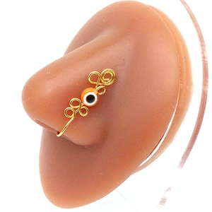 Close-up of golden wire-wrapped evil eye nose ring on flesh-toned silicone model