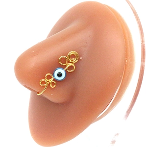 Macro shot of handmade gold wire evil eye nose ring clip with blue bead detail