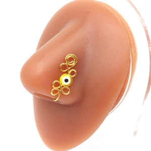 Detail of handmade golden wire-wrapped nose ring with yellow evil eye bead on nose model