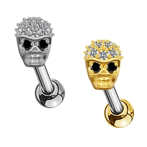 Dettaglio macro di piercing a teschio con zirconi bianchi in finitura argento e oro