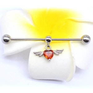 Industrial barbell earring with orange heart gemstone and angel wings on a flower