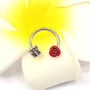 Detail of horseshoe nose ring featuring a silver vintage butterfly and red embossed rose