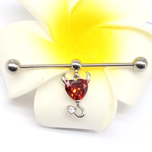 Industrial barbell with red heart gemstone and devil wing elements on flower background