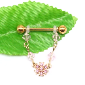Detailed macro view of golden stainless steel barbell piercing with pink crystal flower chain