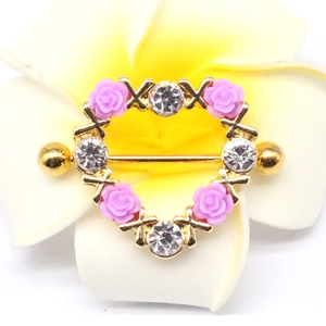 Macro detail of heart-shaped nipple ring with purple roses and clear sparkling zircons