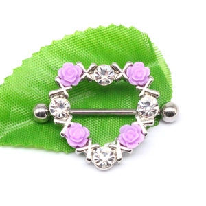 Close-up of heart-shaped nipple ring with purple roses and sparkling rhinestones