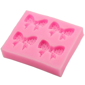 Detailed macro view of pink silicone mold featuring four intricate bow-shaped cavities