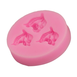 Detail of pink silicone mold featuring three leaf cavities for fondant and chocolate DIY crafts