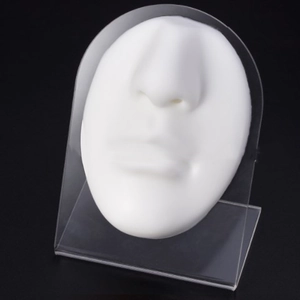 Macro view of white silicone nose and lip model on a transparent acrylic stand for practice