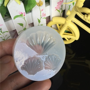 Handheld semi-transparent silicone mold featuring three detailed seashell designs for DIY resin crafts