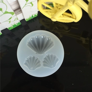 Round silicone mold with three scallop shell cavities for resin DIY on black surface