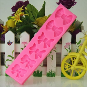 Pink silicone mold featuring 6 assorted bow and cherry ribbon designs for cake decorating