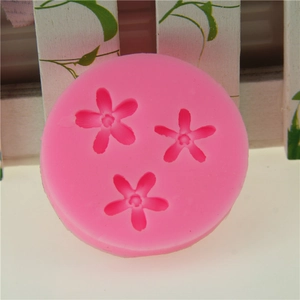 Pink silicone fondant mold with small flower patterns on a white wooden background
