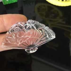 Handheld view of a transparent fan-shaped mold with intricate rose and bird patterns