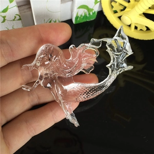 Transparent mermaid-shaped resin pendant with detailed scale textures on a mirrored surface