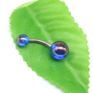 Piercing de nombril incurvé en acrylique bleu irisé sur fond de feuille verte