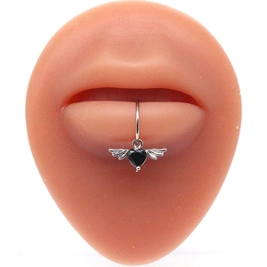 Detail of a lip ring featuring a black heart gemstone with wings on a silicone model