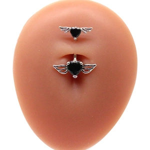 Dettaglio del piercing all'ombelico con cuori neri e ali d'argento su modello