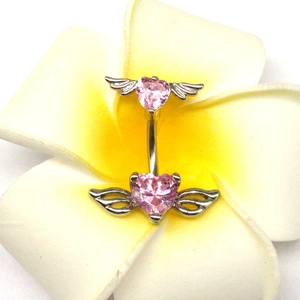 Dettaglio del piercing all'ombelico con cuore rosa e ali d'angelo su un fiore