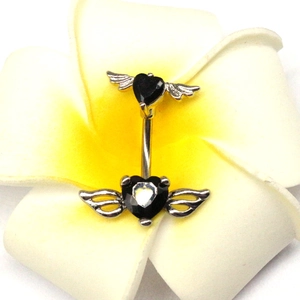 Dettaglio di piercing all'ombelico a cuore gotico con ali su fiore giallo