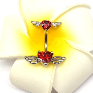 Piercing per ombelico a ali di cuore con pietre rosse su un fiore di frangipane bianco
