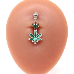 Macro detail of silver maple leaf belly ring with vibrant green glitter finish