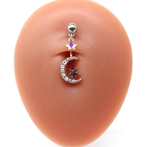 Macro detail of crescent moon and star belly ring with white rhinestones on model
