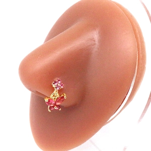 Macro detail of golden nose ring with pink butterfly and flower charms on model