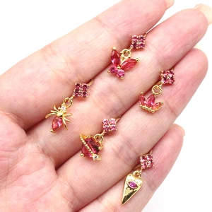 Close-up of five gold nose studs with pink crystals, butterfly and crown shapes