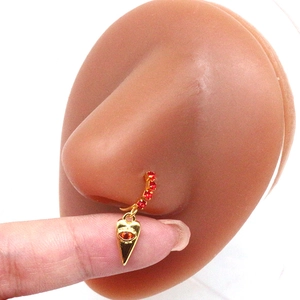Detailed shot of golden heart nose ring with evil eye and red rhinestones on a model