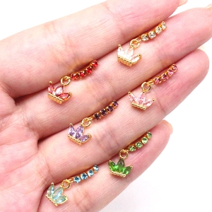 Macro shot showing six colorful crown piercing studs in various gemstone shades on palm