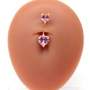 Détail d'un piercing de nombril doré orné de zircons roses en forme de cœur sur modèle
