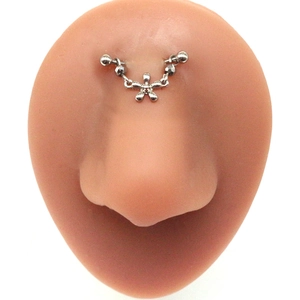 Detail of silver bridge piercing with chain and star pendant on silicone nose model