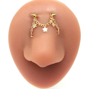 Detail of gold piercing bridge chain featuring star charms and punk style cone spikes