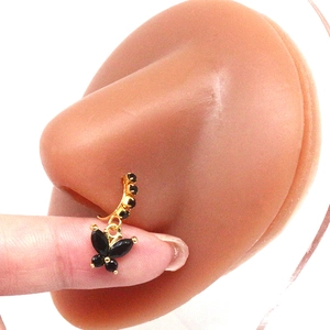 Close-up of golden nose ring with black butterfly pendant on silicone model