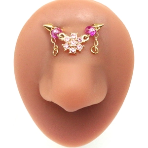 Macro detail of golden bridge piercing with pink flower rhinestones and hanging chains