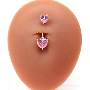 Vue macro d'un piercing nombril avec zircons cœurs roses sur un modèle en silicone
