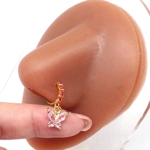 Detail of gold nose ring with pink butterfly pendant shown on a nose model