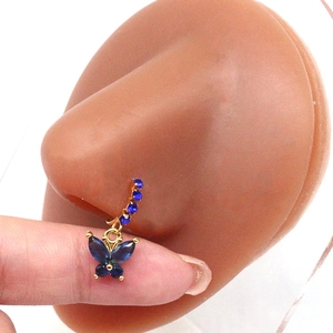 Detailed view of a golden butterfly nose ring with blue zircon stones on a silicone model