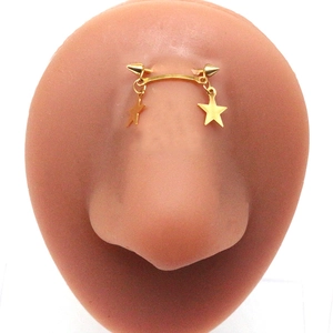Gold stainless steel bridge piercing with double star pendants and cone ends on model
