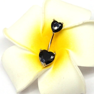 Vue rapprochée du piercing nombril cœur doré avec zircons noirs sur une fleur