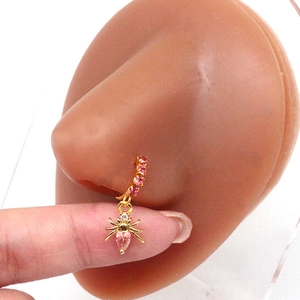 Detail of gold spider nose ring with pink pear-shaped stone on a silicone model